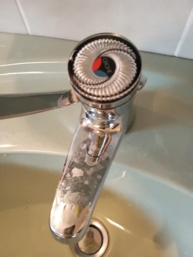 Ein Wasserhahn mit einem spiralförmigen Auslauf und kühlem Wasser.