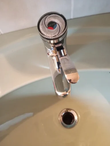 Ein moderner Wasserhahn über einem Abfluss in einem Waschbecken.